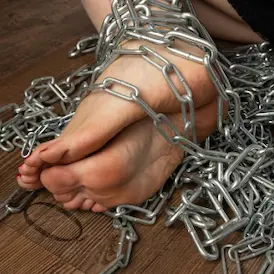 Soles of Lady Samantha's bare feet with red toenails, bound in heavy metal chains - Foot Fetish Zurich